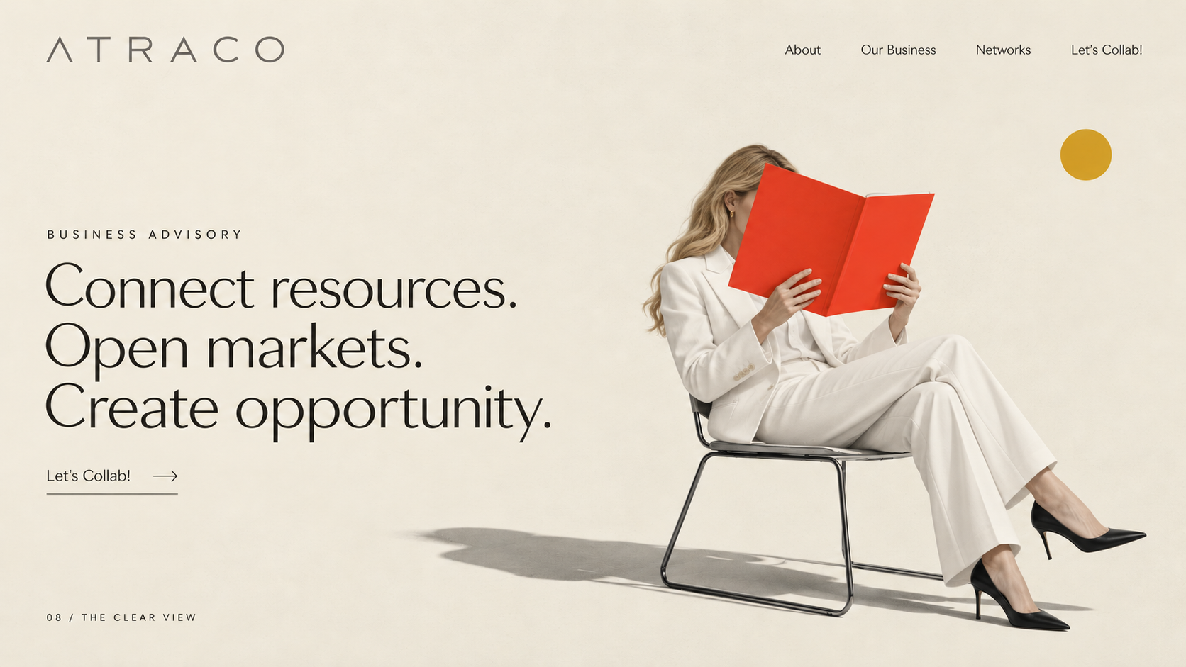 A blonde woman in a white trouser suit reading a red book